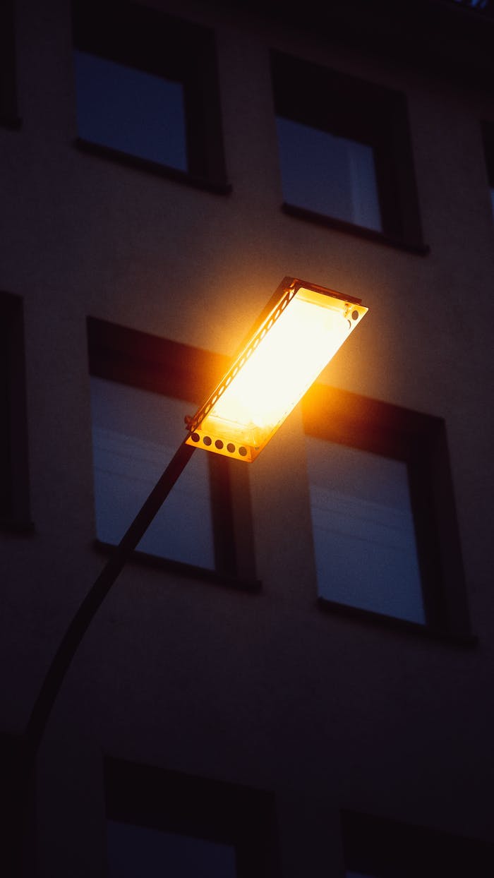 hero-about Close-up of a bright streetlight casting a warm glow against a building background.